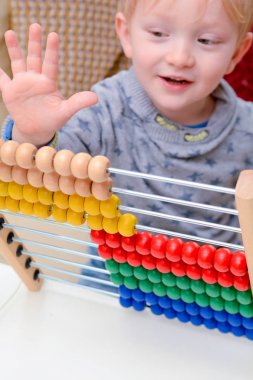 Çocuk saymayı öğreniyor. Genç çocuk matematik öğrenmek için bir abaküs kullanarak