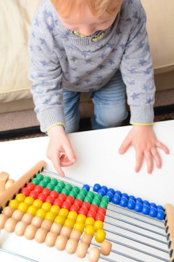 Çocuk saymayı öğreniyor. Genç çocuk matematik öğrenmek için bir abaküs kullanarak