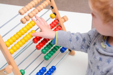 Çocuk saymayı öğreniyor. Genç çocuk matematik öğrenmek için bir abaküs kullanarak