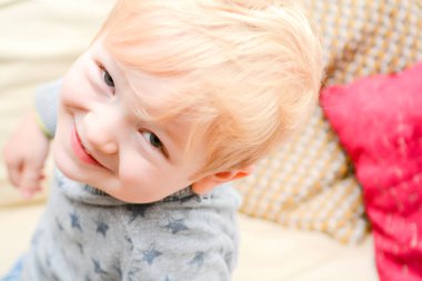 Evde mutlu çocuk doğrudan kameraya bakıyor. Sevimli sarışın çocuk i