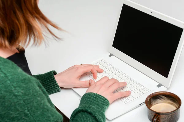 Une femme utilisant un ordinateur portable assis à un bureau blanc — Photo