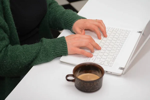 Une femme utilisant un ordinateur portable assis à un bureau blanc — Photo