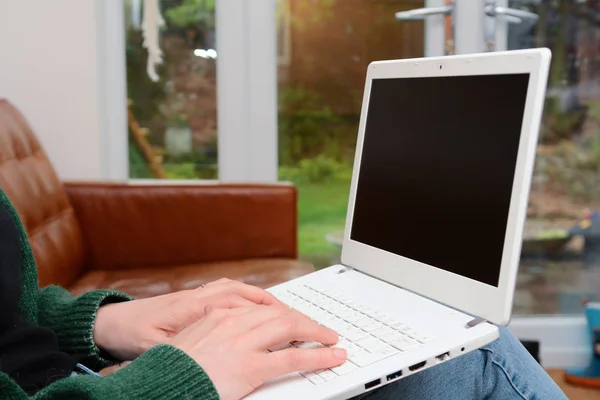 Femme à la maison en utilisant un ordinateur portable tout en se relaxant sur le canapé — Photo