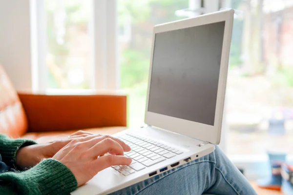 Femme à la maison en utilisant un ordinateur portable tout en se relaxant sur le canapé — Photo