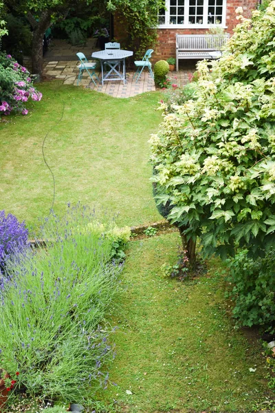 A well kept back yard or garden with lawn and seating area, high