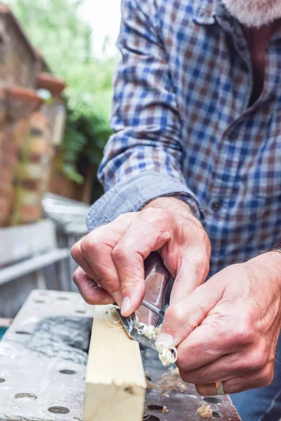 Close-up van Mans handen werken met een vliegtuig op houten plank — Stockfoto