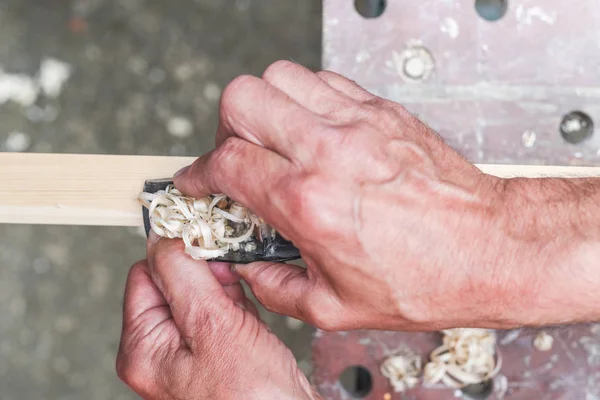 Close-up van Mans handen werken met een vliegtuig op houten plank — Stockfoto