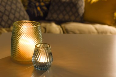 Bir aile evinin içinde, içi mumla dolu rahat bir oda. 