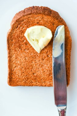 Eriyen tereyağı ve bıçakla beyaz bir tabakta sıcak tost dilimi