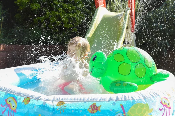 子供は庭のプールで水遊びを楽しんでいます少年は幸せで笑顔です — ストック写真