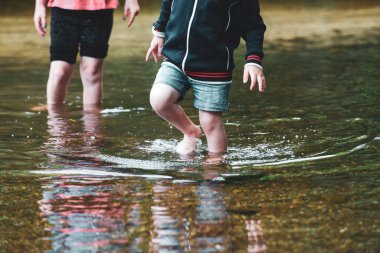 Çocuklar güneşli bir günde birlikte bir su deresinde kürek çekerler.