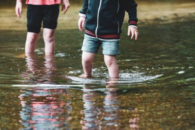 Çocuklar güneşli bir günde birlikte bir su deresinde kürek çekerler.