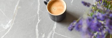 Evdeki mermer bir masada kahve ve çiçekler.