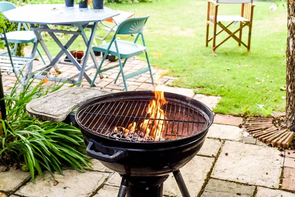 Bbq grill with flames in an empty back garden preparing to cook outside