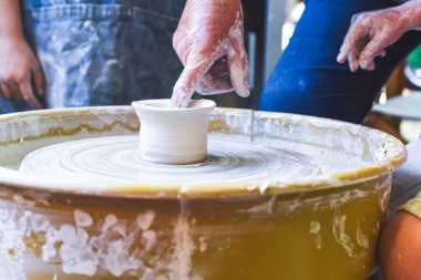 Çocuklar seramik dersinde kilden çömlek yapıyorlar.