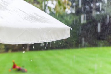 Sağanak yağış sırasında bahçe şemsiyesinden sağanak yağmur yağıyor