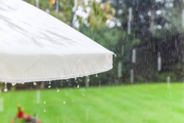 Sağanak yağış sırasında bahçe şemsiyesinden sağanak yağmur yağıyor