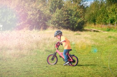Genç okul çocuğu bisikletiyle tarladan geçiyor.