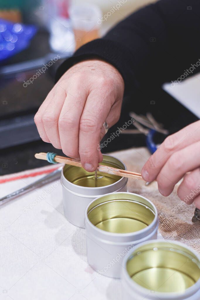 A Chandler or candle maker adds a wick to scented hand made candles