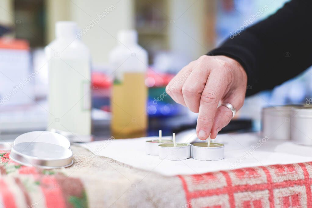 A Chandler or candle maker adds a wick to scented hand made candles