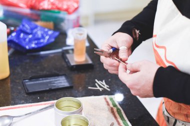 Chandler veya mum imalatçısı kokulu el yapımı mumlara fitil ekler.