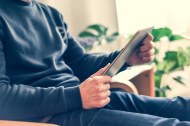 Bir erkek e-posta ve sosyal medya mesajlarını kontrol etmek için evde kablosuz tablet kullanıyor