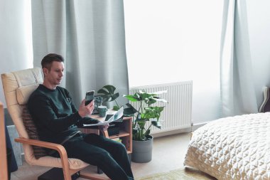 Evde çalışan bir adam toplantı sırasında telefonla konuşuyor.