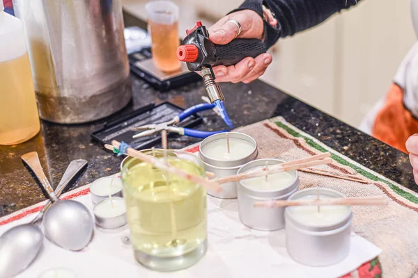 Creative occupation of candle making showing the pouring of liquid wax into jars