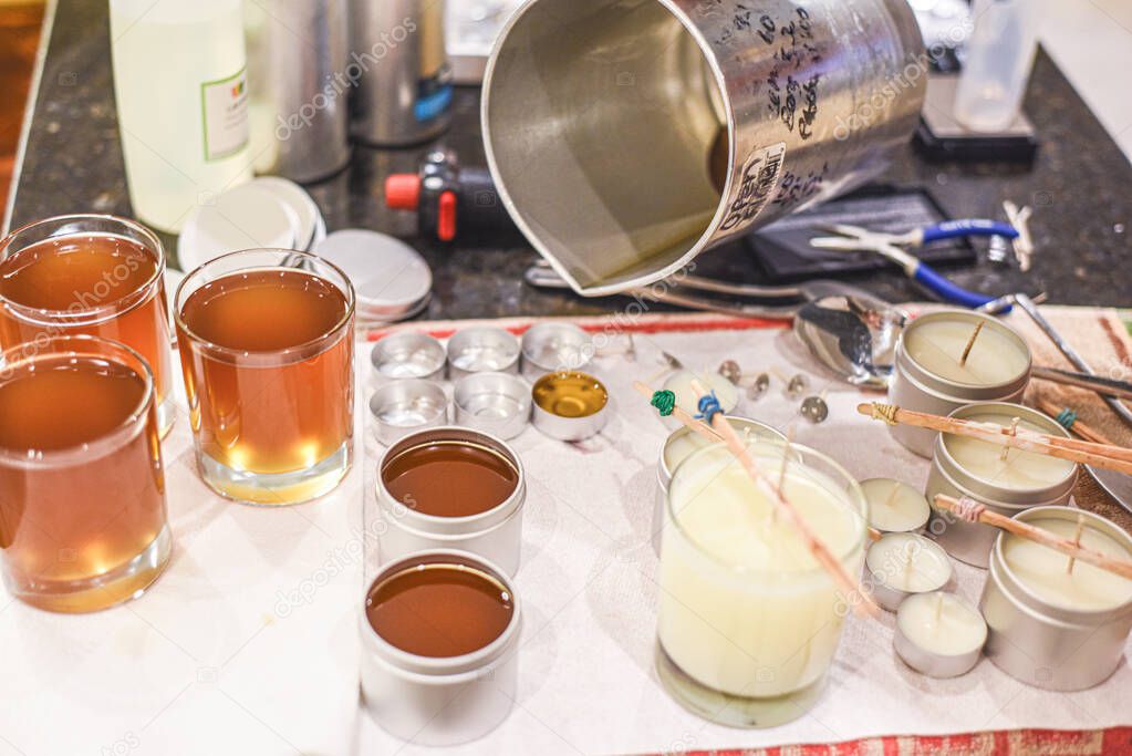 Creative occupation of candle making showing the pouring of liquid wax into jars