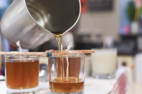 Creative occupation of candle making showing the pouring of liquid wax into jars