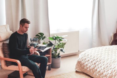 Evde çalışan bir adam toplantı sırasında telefonla konuşuyor.