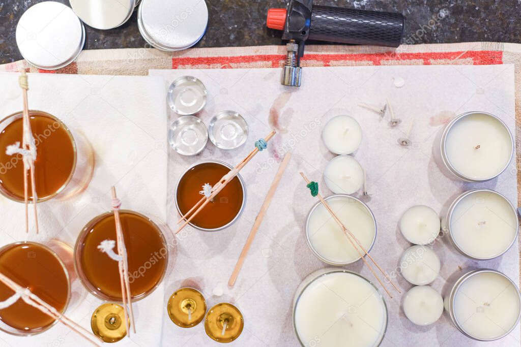 Creative occupation of candle making showing the pouring of liquid wax into jars