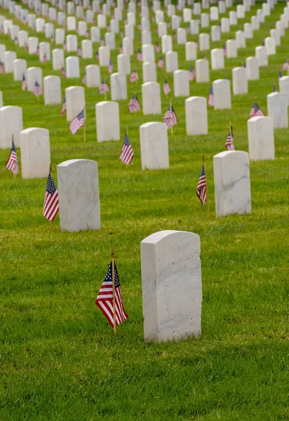 Lápidas blancas en el cementerio nacional con banderas pequeñas — Foto de Stock