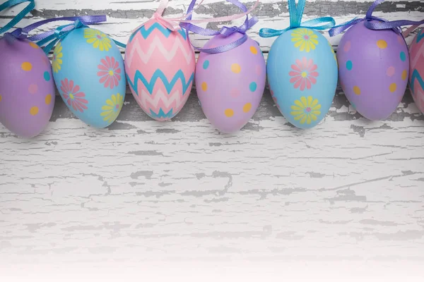 A group of pastel colored Easter eggs on a white wooden background
