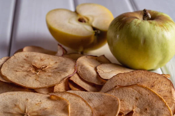 Close up dried apple fruit chips and fresh apples on white background .