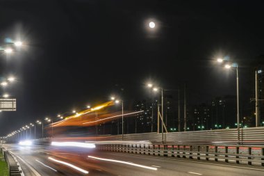 Işıklı karayolu ve gece şehri üzerinde yükselen ay,