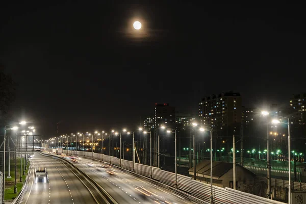 Işıklı karayolu ve gece şehri üzerinde yükselen ay,