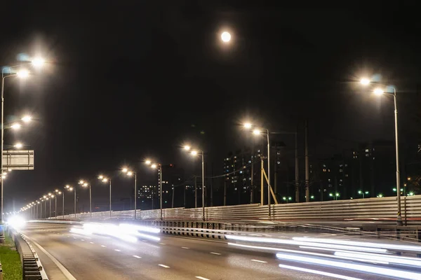 Işıklı karayolu ve gece şehri üzerinde yükselen ay,