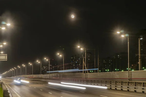 Işıklı karayolu ve gece şehri üzerinde yükselen ay,