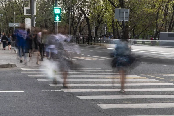 Traffic flows of people and cars at the busy city crossroad