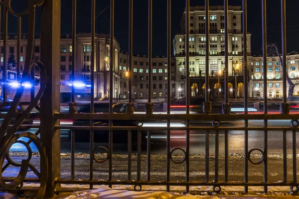 Tiro do tráfego noturno feito através de uma cerca de ferro fundido — Fotografia de Stock