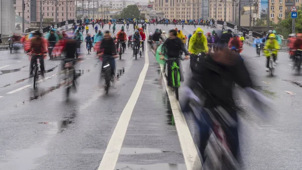 骑自行车穿过城市的中央街道在雨中 图库图片