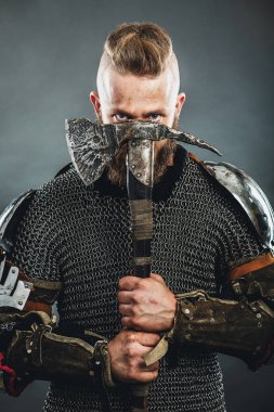 Ortaçağ savaşçısı dövmeli ve baltalı derili Viking düşmana saldırıyor. Konsept tarihi fotoğraf