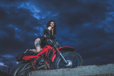 Seksi esmer motorcu kız bir motosiklet üzerinde oturur