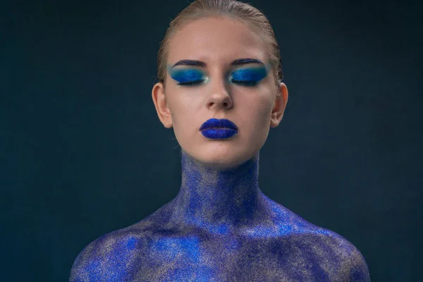 Portrait d'une fille parsemée de paillettes bleues avec un maquillage lumineux — Photo