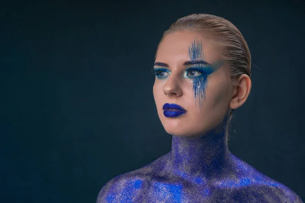 Portrait of a girl in cosmic make-up, a body dotted with sequins on a dark background