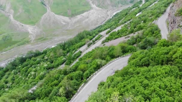 Fotografía aérea. Colinas verdes, montañas y un camino de entrada, una vista desde una altura. 4K — Vídeo de stock