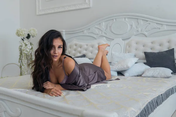 Mooie brunette meisje in sexy lingerie poseren op een bed — Stockfoto