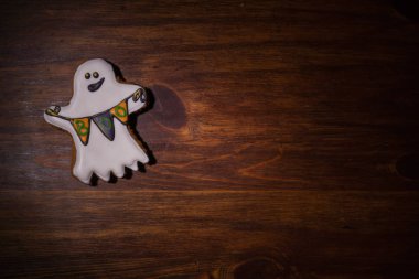 Gingerbread tahta bir masanın üzerinde yatan bayraklı hayaletler şeklinde rakam. Cadılar Bayramı için hazırlanıyor