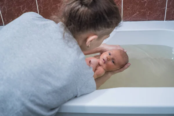 Mujer bañando al bebé en el baño. Masaje de bebé en agua tibia. Recuperación —  Fotos de Stock